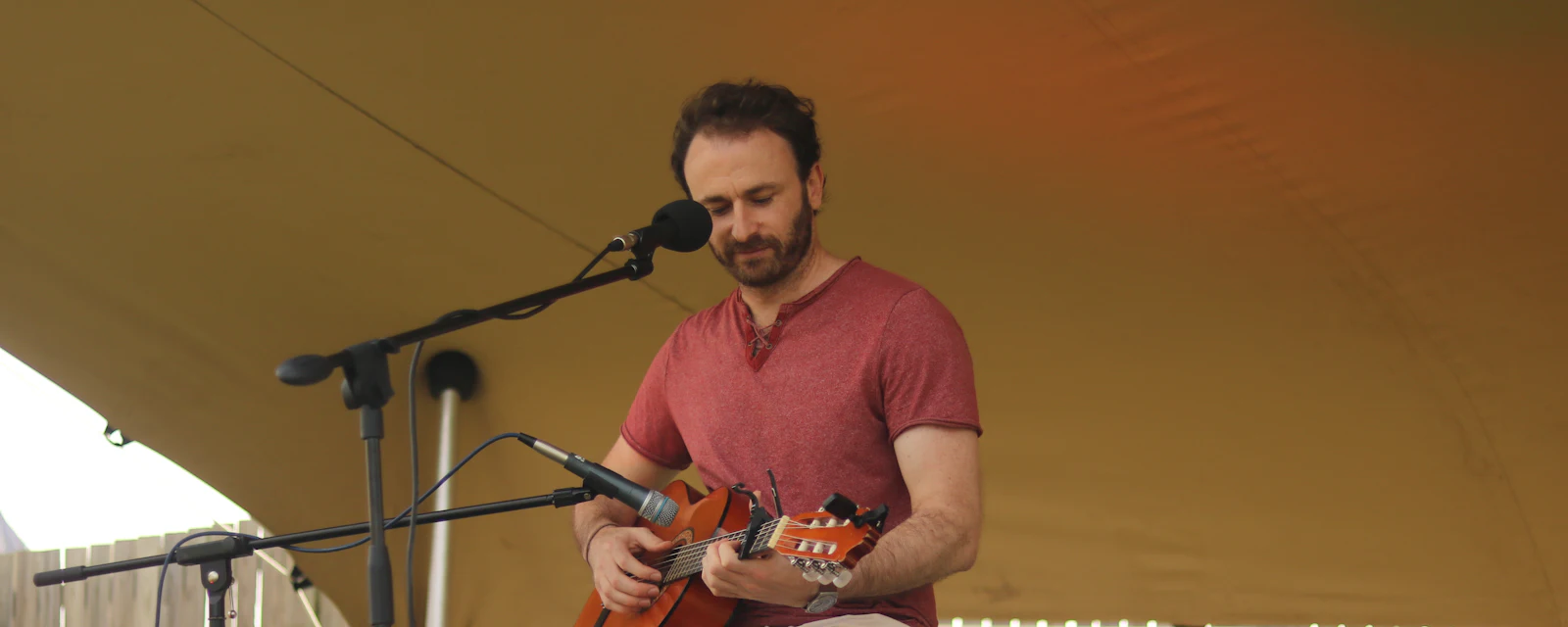Performer singing into a microphone while playing guitar at an open mic night