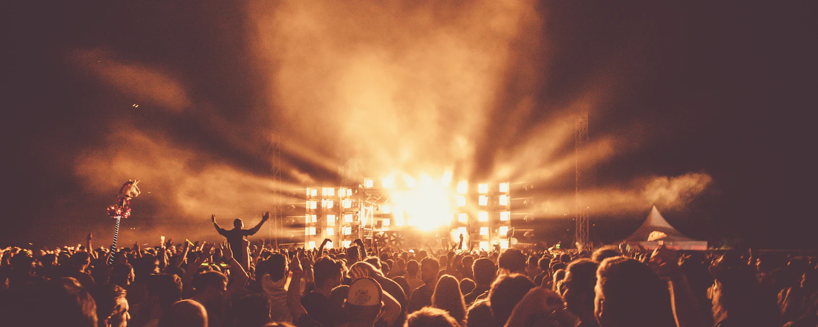 Outdoor summer concert stage glowing over a happy crowd at dusk